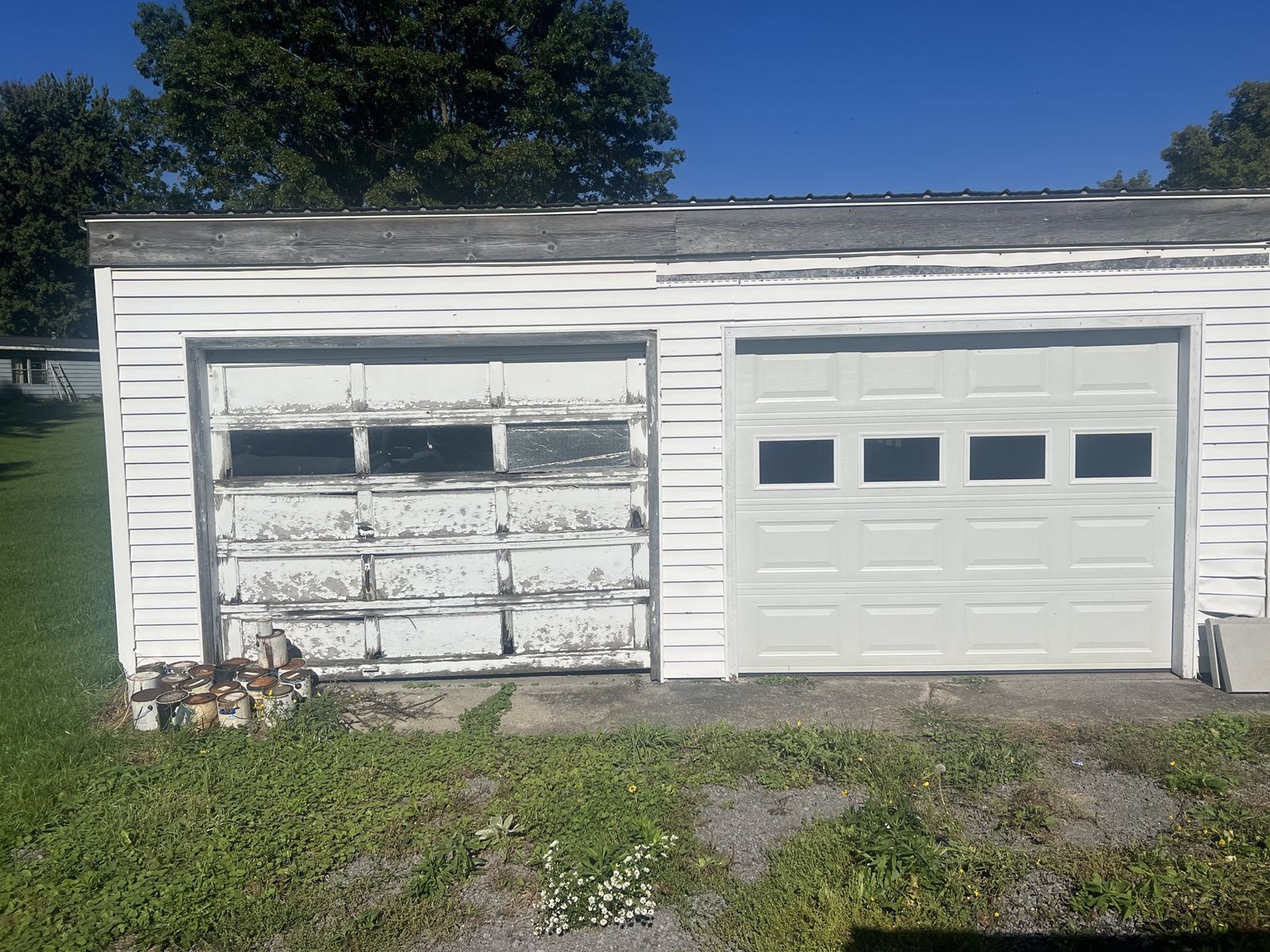 Old wooden garage door next to a new white garage door