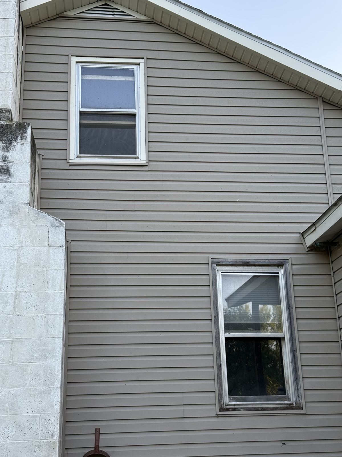 House wall finished with tan vinyl siding